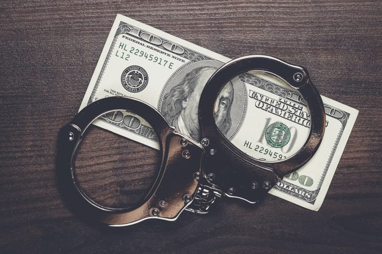 handcuffs and one hundred dollars on wooden table