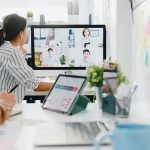 Asia businesspeople using desktop talk to colleagues in video call meeting in office.