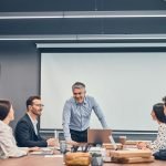 Smiling colleagues discussing new startup project with boss in office