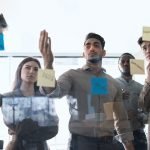 Colleagues having meeting using sticky post-it notes on glass wall