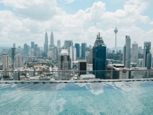 View of Kuala Lumpur’s skyline with the Petronas Tower from a roof top with a pool