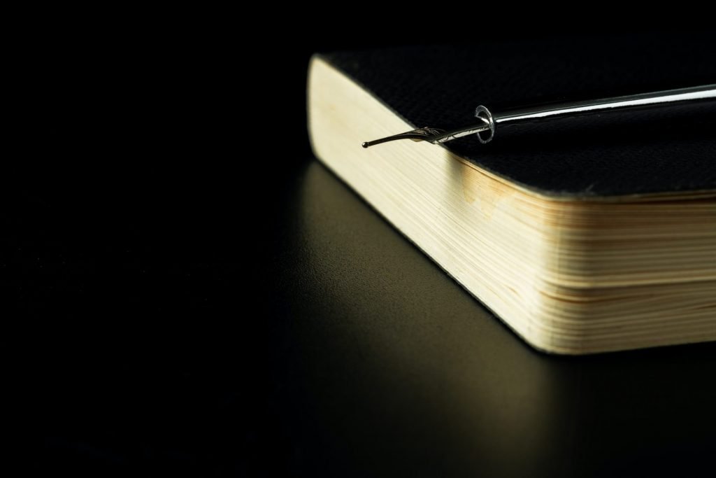 Black notepad with pen on black table close up