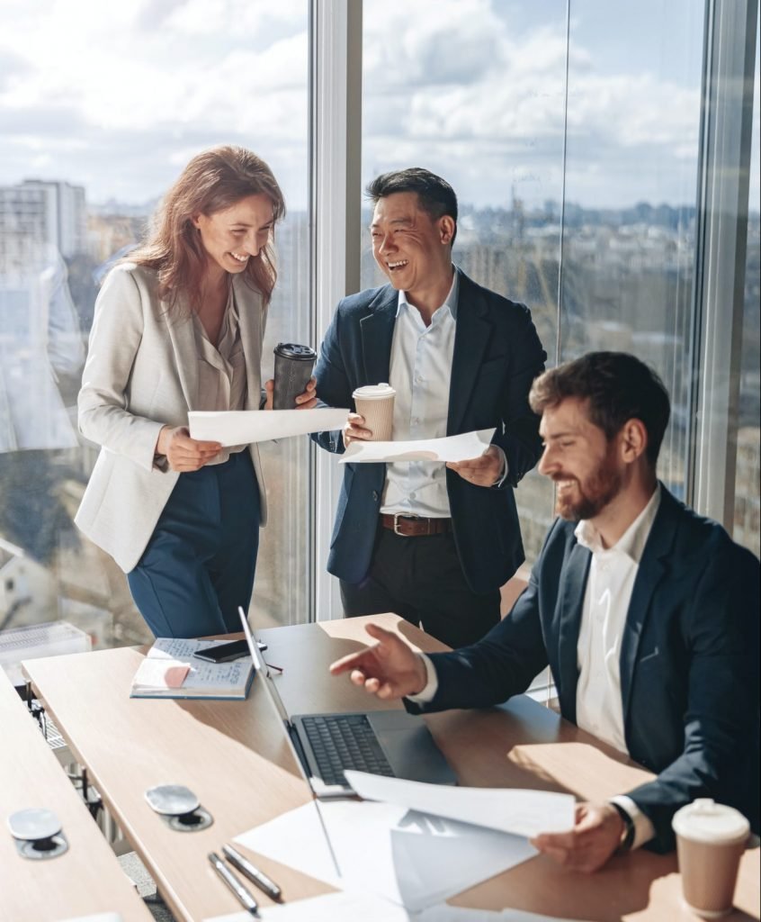 Smiling businessmen drink coffee and discussing documents with graphs and charts